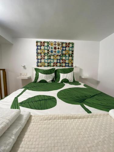 um quarto com uma cama grande com lençóis e almofadas verdes em Estudio Deluxe Hercules em Sevilha