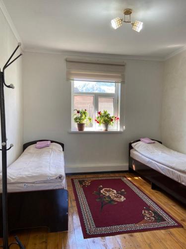 a room with two beds and a window and a rug at Guest House Azaliya, Сары-Челек гостевой дом Азалия in Arkit