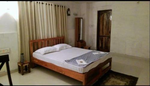 a bedroom with a bed with a wooden head board at The Sattva Nature Retreat in Avathi