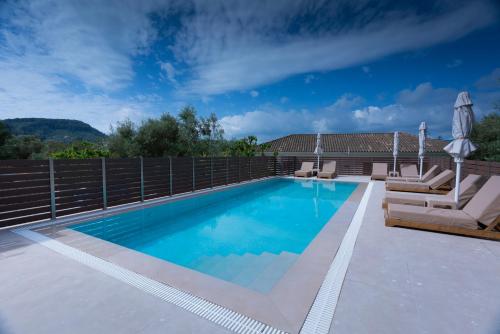una piscina con due sedie a sdraio e una recinzione di Small Village Residences ad Akrotiri