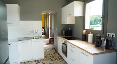 a kitchen with white cabinets and a sink and a window at MARA RIVIERE gîte d'étape sur la vélo Francette in La Jaille-Yvon