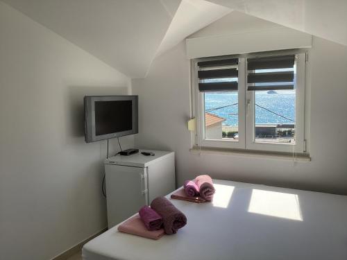 a room with a tv and two towels on a bed at Apartments Ploka in Trogir