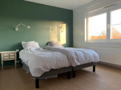 a bed in a bedroom with a green wall at Maison spacieuse avec piscine au sel proche grand stade in Sainghin-en-Mélantois