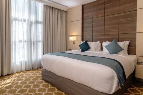 a hotel room with a large bed and a large window at Swiss International Taif in Taif