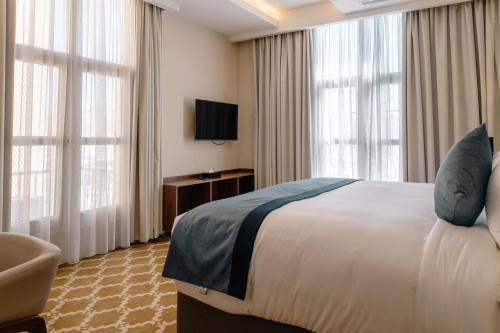 a hotel room with a bed and a tv and windows at Swiss International Taif in Taif
