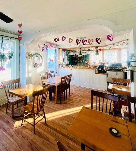a restaurant with wooden tables and chairs and a kitchen at Les Pinsons des Rives in La Malbaie