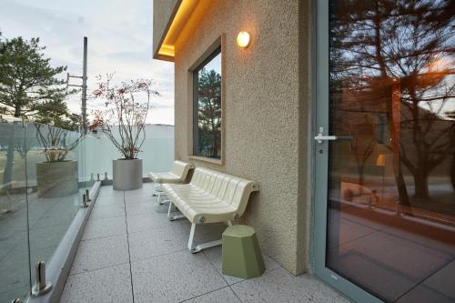 two white benches sitting on the side of a building at PBr7 Hotel Unusual Stay in Gyeongju