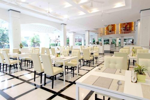 a dining room with white tables and chairs at Pooh Beach Resort & Spa in Jomtien Beach