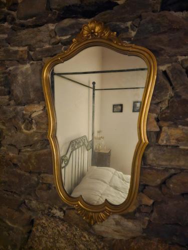 a mirror on a stone wall with a bed at Segredo do Castelo do Sabugal in Sabugal