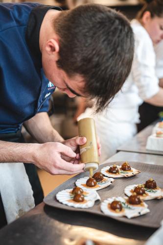 a man is preparing food on a table at Logis Hôtellerie Les Brisants , Restaurant J M Perochon in Brétignolles-sur-Mer
