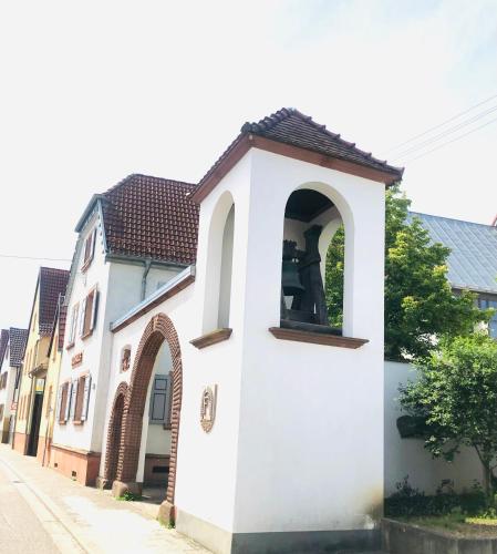a small white building with an arch on a street at Ferienwohnung Feldmann in Freckenfeld