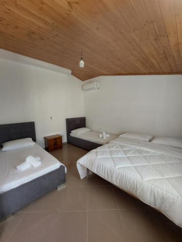 1 dormitorio con 2 camas y techo de madera en Guest House Xhaferaj en Berat