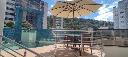 a patio with a table and chairs and an umbrella at Horto Executivo Hotel in Ipatinga