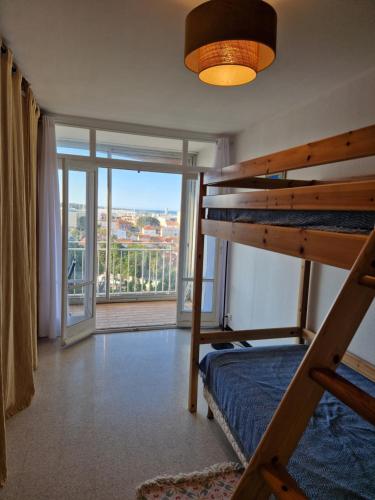 une chambre avec un lit superposé et une grande fenêtre dans l'établissement Location appartement bord de mer, à Canet