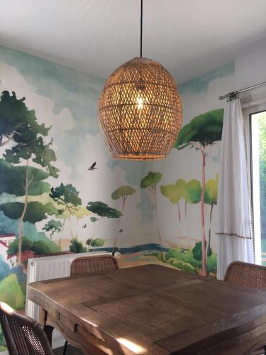une salle à manger avec une table et un lustre dans l'établissement Maison lumineuse entre terre et mer, à Séné