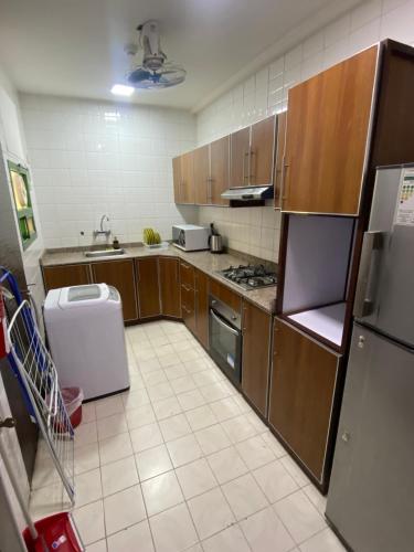 a large kitchen with wooden cabinets and a refrigerator at Rest-Inn Furnished Apartments ريست-ان للشقق المفروشة in Muscat