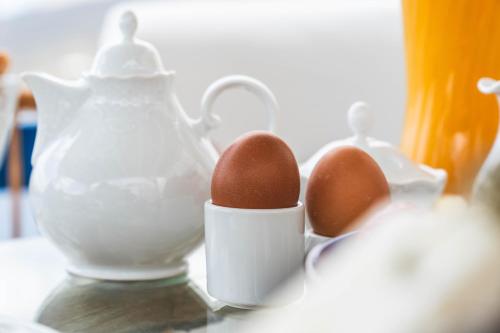 two eggs in a white container next to a tea pot at Studios Kilindra in Astypalaia Town