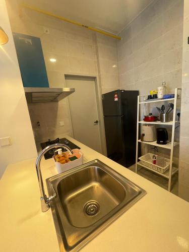 a kitchen with a sink and a black refrigerator at Indah@Antara Putrajaya in Putrajaya