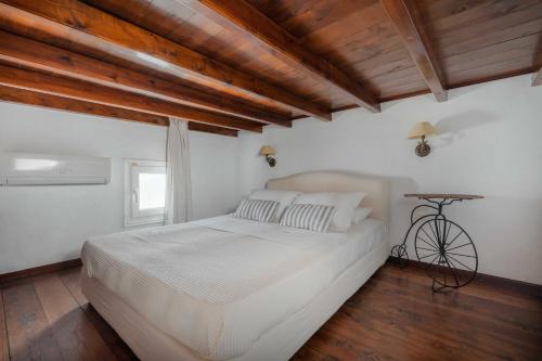 a bedroom with a white bed and wooden ceilings at Studios Kilindra in Astypalaia Town