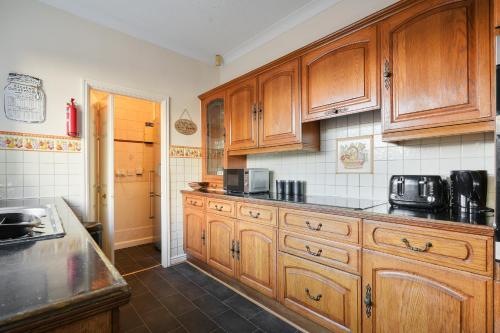 a kitchen with wooden cabinets and a black counter top at HILLTOP PLACE SUITES M1 J31 near PEAK DISTRICT 