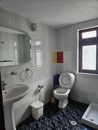 a bathroom with a white toilet and a sink at Apartamente plazhi in Sarandë