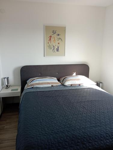a bed with a black comforter and two pillows at Apartments Frigan in Maslenica