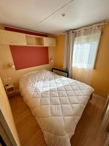 a bedroom with a white bed and a window at Mobil home camping Lalande Mimizan in Mimizan