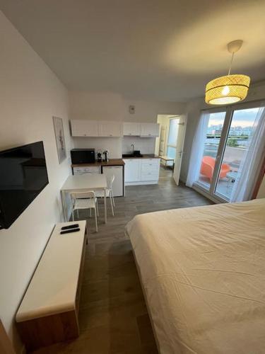 Cette chambre comprend un lit, une table et une cuisine. dans l'établissement Le Qwartz - vue stade de France, à Villeneuve-la-Garenne