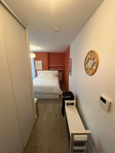 une petite chambre avec un lit et une horloge au mur dans l'établissement Le Qwartz - vue stade de France, à Villeneuve-la-Garenne