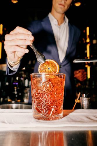 a man in a suit stirring a drink with a spoon at Hotel KÜGLERHOF in Tirolo