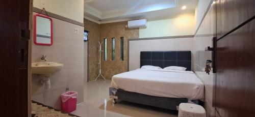 a bedroom with a bed and a bathroom with a sink at CALDERA PARK HOMESTAY Syariah in Probolinggo