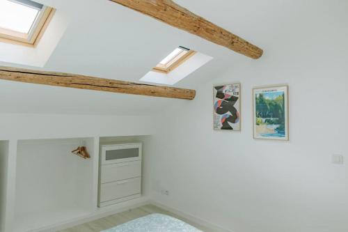 Cette chambre est dotée de murs blancs et de poutres apparentes. dans l'établissement Maison Gilberte - Avec terrasse au coeur du village, à Châteauneuf-du-Pape