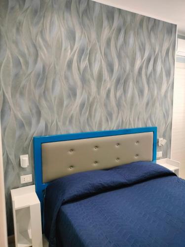 a bedroom with a blue bed and a wall at Casa Acquamarina in Marina di Monasterace