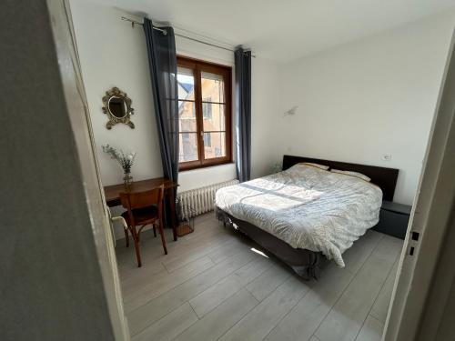 a bedroom with a bed and a desk and a window at Sereine d'Argouges in Bayeux