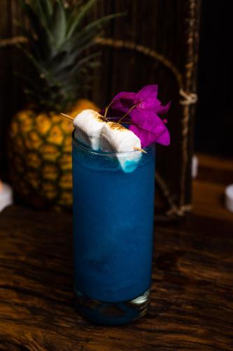 a blue drink sitting on a table with a purple flower at Sie Casa Hotel in Villa de Leyva