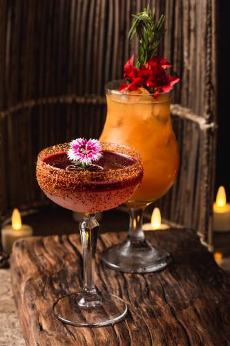a drink and a vase with a flower on a table at Sie Casa Hotel in Villa de Leyva