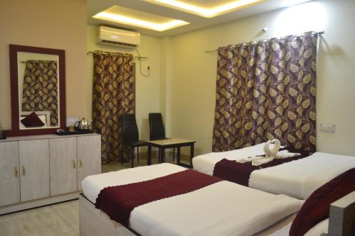 een hotelkamer met 2 bedden en een bureau bij O'SKY INN in Siliguri
