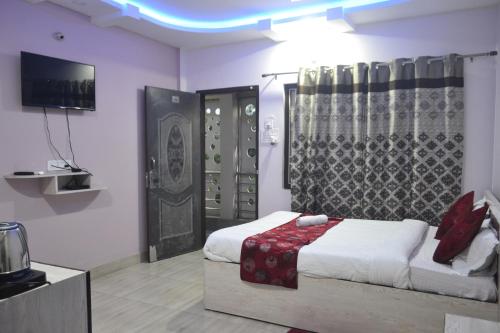 um quarto com uma cama e uma televisão num quarto em O'SKY INN em Siliguri