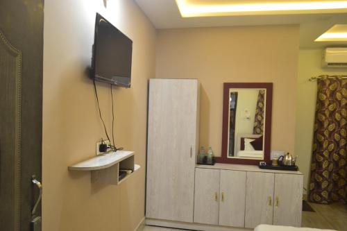 uma casa de banho com uma televisão na parede e um espelho em O'SKY INN em Siliguri