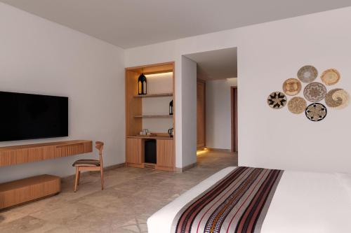 Habitación de hotel con cama y TV de pantalla plana. en The Club by Fanar en Salalah