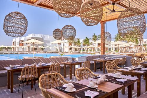 a restaurant with tables and chairs and a pool at The Club by Fanar in Salalah
