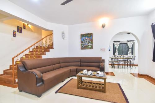 a living room with a brown couch and a table at Nature Villa, Dukes Den Khandala in Khandala