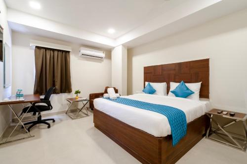 ヴィジャヤワーダにあるMonday Hotels Swarna's The Capitalのベッドとデスクが備わるホテルルームです。