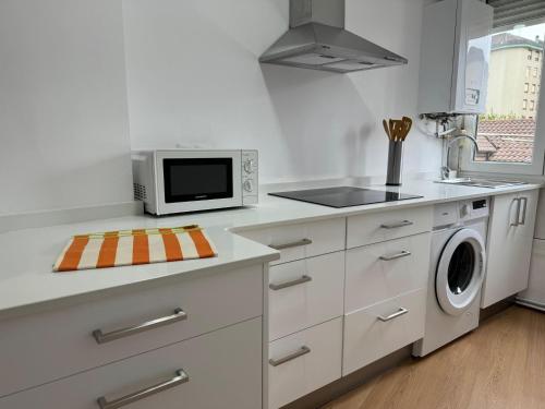 cocina blanca con microondas y fogones en Fantástico apartamento cerca de Santander en El Astillero
