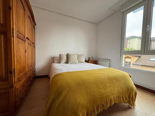 Un dormitorio con una cama con una manta amarilla. en Fantástico apartamento cerca de Santander en El Astillero