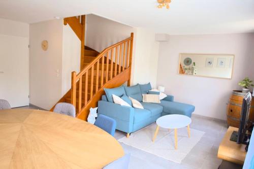 ein Wohnzimmer mit einem blauen Sofa und einem Tisch in der Unterkunft Maison calme avec jardin proche de Toulouse in Odars