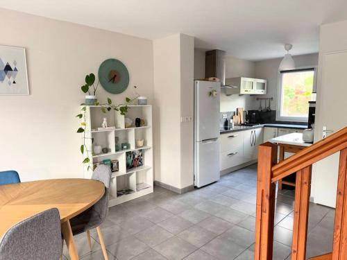 eine Küche mit einem Tisch und einem weißen Kühlschrank in der Unterkunft Maison calme avec jardin proche de Toulouse in Odars