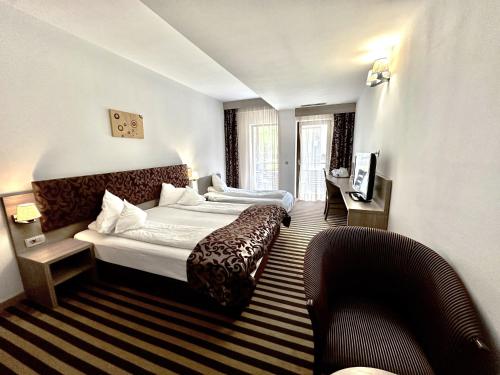 a hotel room with two beds and a couch at Hotel TISA in Băile Olăneşti