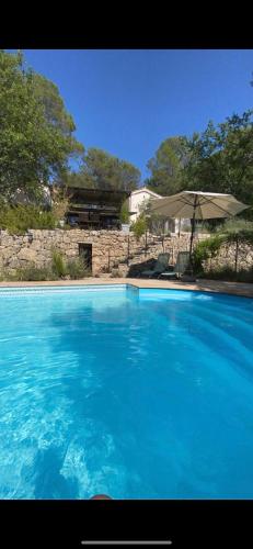 une grande piscine bleue avec un parasol dans l'établissement La cachette, à Carcès