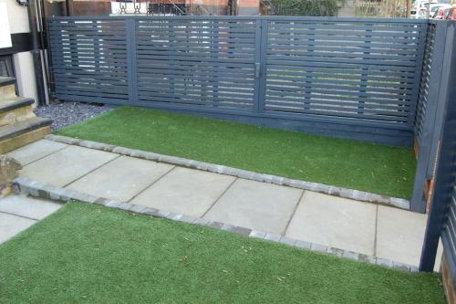 a fence with green grass in front of a house at Self contained studio apartment in Burley, Leeds in Headingley